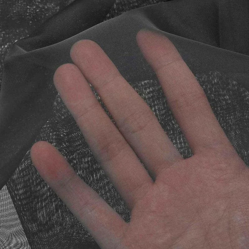 Main en gros plan touchant un tissu fin et transparent, illustrant la légèreté et la texture délicate du produit idéal pour la confection de vêtements, doublures ou accessoires.