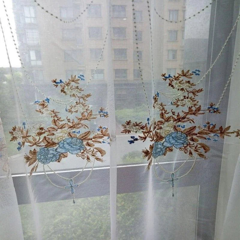 Rideau brodé floral transparent, idéal pour ajouter une touche élégante et décorative à votre intérieur. Le design subtil avec des motifs floraux en bleu et marron rehausse n'importe quelle pièce, offrant une ambiance lumineuse et apaisante. Solution parfaite pour ceux qui souhaitent combiner esthétique et fonctionnalité dans leur décoration de fenêtres.