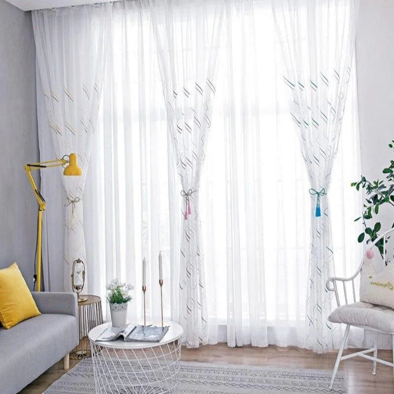 Salon moderne avec rideaux légers et transparents, apportant une ambiance lumineuse. Le décor comprend un canapé gris avec un coussin jaune vif, une lampe de lecture jaune élégante, et une table basse en métal blanc avec des accessoires décoratifs. Les rideaux ajoutent une touche de sophistication et d'élégance à la pièce.