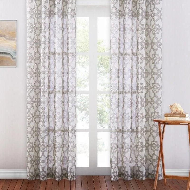 Rideaux élégants avec motifs géométriques, parfaits pour ajouter une touche moderne à tout intérieur. Idéal pour filtrer la lumière tout en préservant l'intimité. S'intègre parfaitement dans un salon ou une chambre à coucher. Montés sur une tringle au-dessus d'une grande porte-fenêtre, ils complètent un décor contemporain.