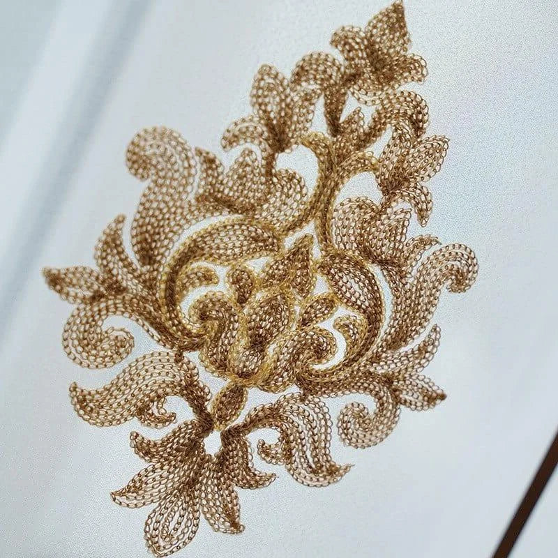 Détail d'un motif brodé élégant en arabesque dorée sur fond clair, idéal pour la décoration intérieure raffinée. Élément artistique orné, parfait pour ajouter une touche de luxe et de sophistication à votre espace de vie. Design complexe et attrayant, inspiré par l'art traditionnel. Convient pour les amateurs de décoration d'intérieur à la recherche d'un style classique et chic.