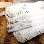 Napkin élégante avec broderies artistiques de couleur beige sur fond blanc, idéale pour décorer une table. Accessoire parfait pour les occasions spéciales, ajoutant une touche de raffinement et de style à votre décoration d'intérieur.
