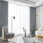 Salon moderne et élégant avec un canapé confortable et un fauteuil design, mettant en avant une table basse stylée sur un sol en marbre. Rideaux contemporains encadrant une grande fenêtre, créant une atmosphère lumineuse et accueillante. Ambiance raffinée, idéale pour un intérieur tendance.