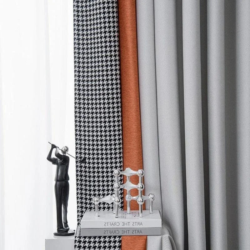 Rideaux modernes et élégants avec différents motifs géométriques, comprenant un design à pied-de-poule noir et blanc, une teinte unie orange et une couleur grise sobre. Accessoire décoratif en métal représentant un golfeur, posé à côté de livres artistiques, créant une ambiance contemporaine dans le salon.