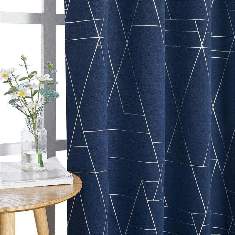Rideau bleu foncé avec motifs géométriques blancs, idéal pour une décoration moderne. Le vase transparent avec des fleurs blanches sur une table en bois ajoute une touche de naturel et d'élégance à l'ensemble.