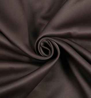 Tissu de couleur marron foncé, soigneusement enroulé, idéal pour la couture et la décoration intérieure. Ce textile est parfait pour apporter une touche d'élégance et de chaleur à votre intérieur.