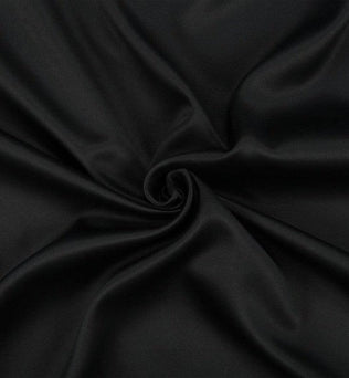 Image d'un tissu noir élégant, idéal pour la couture et la décoration. Ce tissu est parfait pour créer des vêtements sur mesure ou des projets de design intérieur moderne. La couleur noire profonde offre une base chic pour diverses applications créatives.