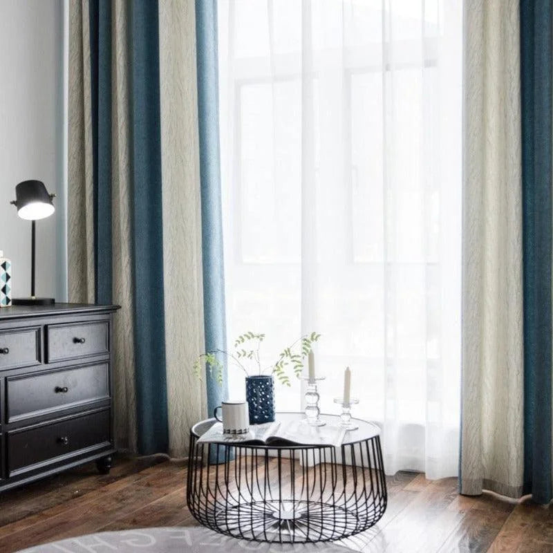 Rideaux élégants pour salon, style moderne et chic, couleurs harmonieuses bleu et beige, lumière naturelle filtrée, ambiance sereine, table basse circulaire en métal noir avec décorations, mobilier contemporain et éclairage subtile.