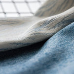 Gros plan sur texture délicate de tissu avec nuances de bleu et beige. Évoque l'élégance et le confort, idéal pour la mode ou la décoration intérieure moderne, apportant une touche subtile et raffinée à votre espace. Parfait pour les amateurs de design élégant et raffiné.