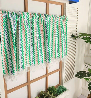 Rideau coloré à motifs zigzag installée dans une décoration intérieure moderne, parfaite pour ajouter une touche vibrante et élégante à votre espace. Ces rideaux uniques disposent d'un design multicolore, intégrant des teintes vertes, orange et bleues, idéal pour illuminer une pièce. Complément idéal pour un aménagement intérieur tendance.