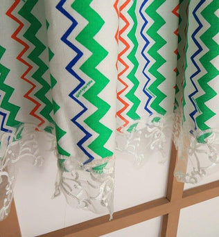 Rideau décoratif à motifs géométriques colorés, verts, bleus et oranges, avec une élégante bordure en dentelle blanche parfaite pour habiller vos fenêtres et apporter une touche moderne et raffinée à votre intérieur. Idéal pour un salon ou une chambre, ce rideau design combine style et originalité.