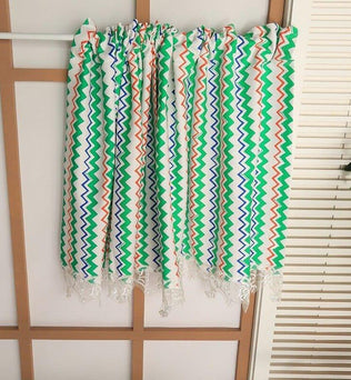 Écharpe colorée avec motifs zigzag multicolores verts, bleus et orangés, idéale pour ajouter une touche de vitalité à votre tenue printanière ou estivale. Accessoire de mode moderne et tendance pour toutes les occasions.