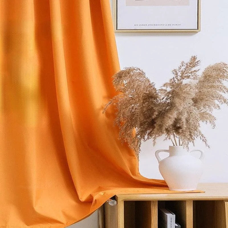Rideau orange décoratif dans un intérieur moderne avec un vase blanc élégant et des herbes séchées, idéal pour ajouter une touche de couleur et de style naturel à votre salon ou chambre.