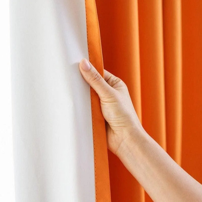 Main tenant un rideau couleur orange et blanc, idéal pour ajouter une touche moderne et colorée à votre intérieur. Parfait pour la décoration de salon ou chambre, facile à installer.
