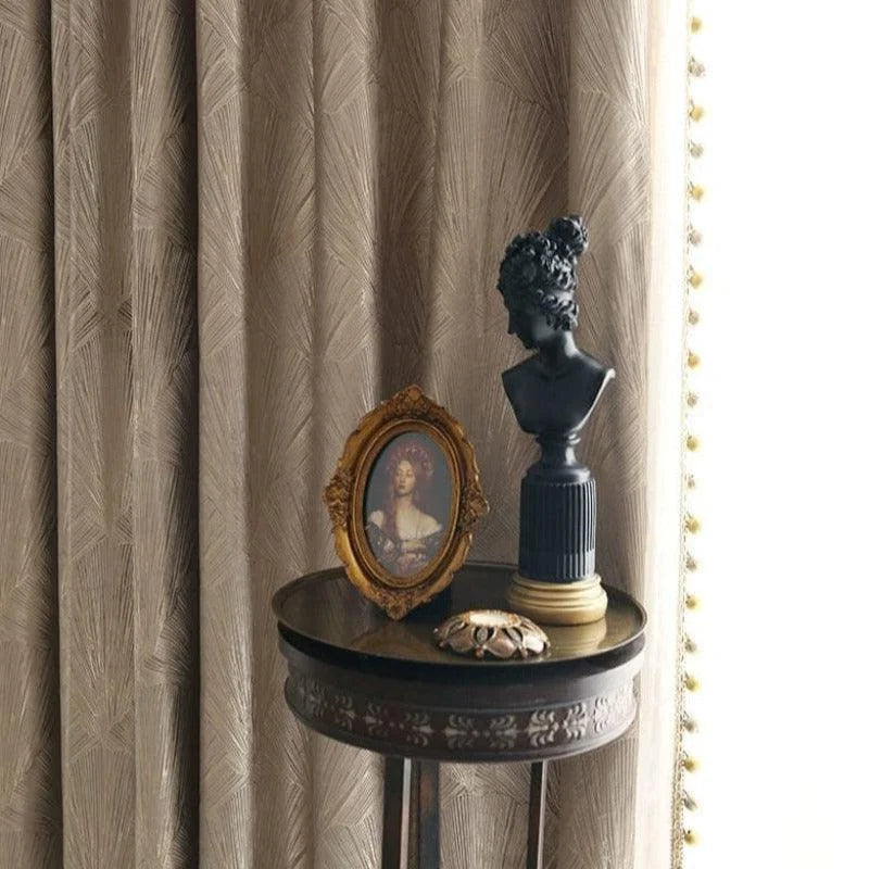 Draperies élégantes présentant un motif subtil, accompagnées d'une table d'appoint classique ornée d'un buste artistique et d'un cadre photo vintage. Décoration intérieure sophistiquée et intemporelle idéale pour un salon distingué.