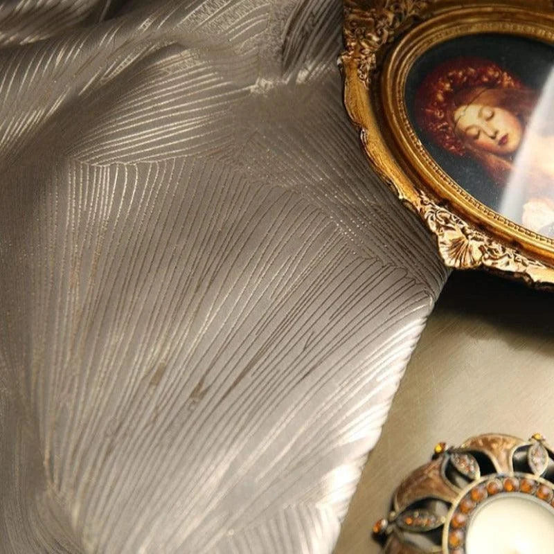 Image représentant un tissu orné d'un motif géométrique raffiné, accompagné d'un cadre décoratif doré encadrant l'image d'une femme. Ce tissu décoratif est idéal pour embellir un intérieur avec une touche de luxe et d'élégance. À ses côtés, un bijou délicat, parfait pour ajouter une note d'éclat sophistiqué à tout espace de vie.