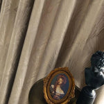 Rideau élégant à motifs subtils, idéal pour ajouter une touche sophistiquée à votre intérieur. Il s'harmonise parfaitement avec des éléments décoratifs classiques comme un cadre orné d'une peinture et une statuette noire. Parfait pour les amateurs de design raffiné et d'atmosphères chaleureuses.