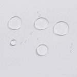 Gouttes d'eau perlant sur une surface blanche, illustrant l'effet déperlant d'un tissu. Protection efficace contre l'humidité pour vos vêtements ou accessoires, idéale pour des conditions humides.