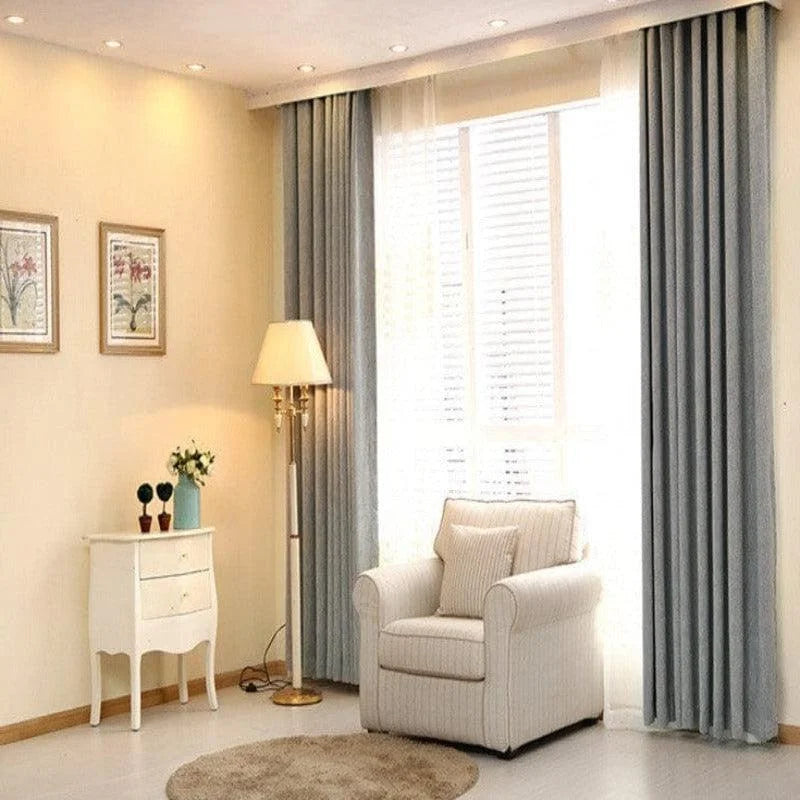 Salon élégant avec fauteuil confortable, rideaux élégants et éclairage d'ambiance. Décoration intérieure raffinée avec un lampadaire classique et un meuble d'appoint chic, idéal pour créer une atmosphère accueillante et moderne. Fenêtre lumineuse pour un espace de vie convivial.