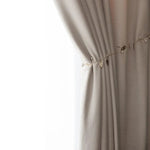 Rideau élégant beige avec un motif texturé, agrémenté d'une chaînette décorative de perles et de petites feuilles dorées, idéal pour apporter une touche de sophistication à votre intérieur. Parfait pour le salon ou la chambre, ce rideau combine design moderne et charme intemporel.