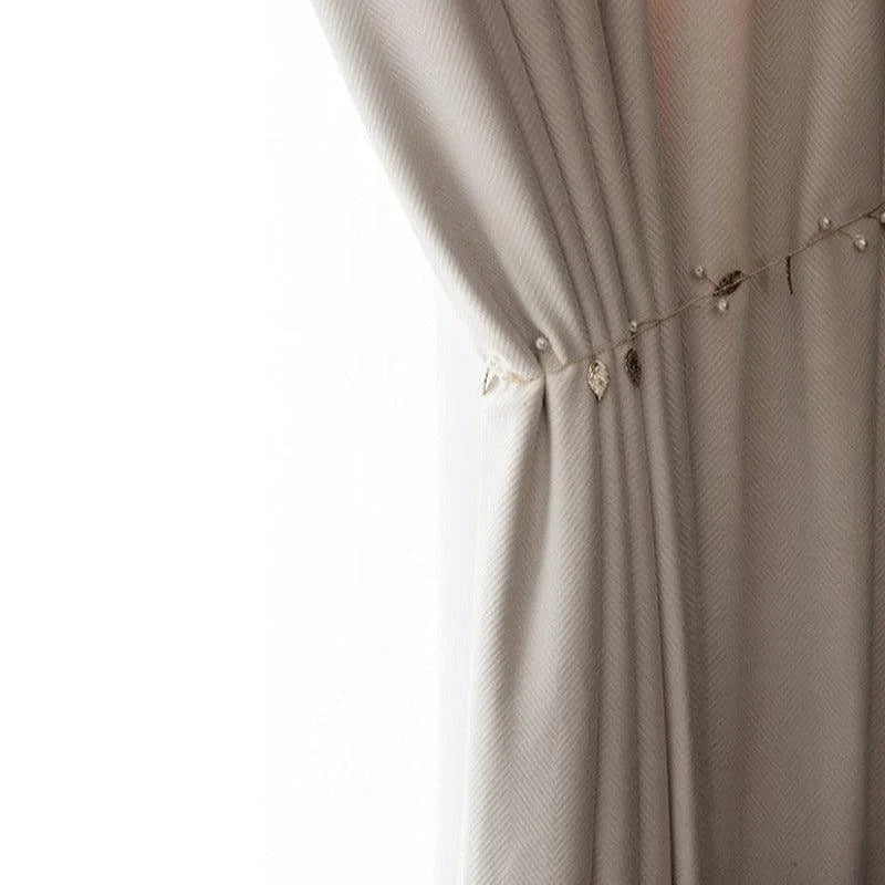 Rideau élégant beige avec un motif texturé, agrémenté d'une chaînette décorative de perles et de petites feuilles dorées, idéal pour apporter une touche de sophistication à votre intérieur. Parfait pour le salon ou la chambre, ce rideau combine design moderne et charme intemporel.