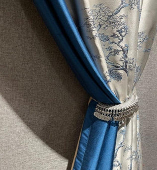 Rideau élégant bleu et gris avec motifs floraux, orné d'un embrasse décoratif, idéal pour ajouter une touche sophistiquée à votre intérieur. Parfait pour le salon ou la chambre, ce rideau crée une ambiance chic et raffinée.