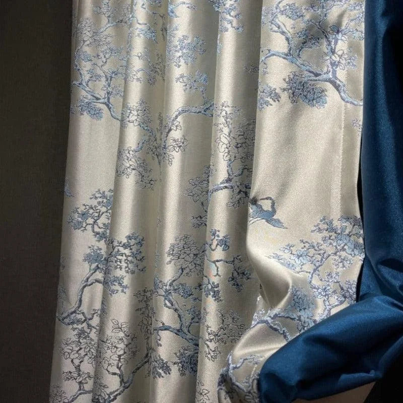 Rideau élégant avec motif de branches florales en bleu sur fond clair, accompagné d'une bande unie bleu foncé. Idéal pour ajouter une touche sophistiquée et naturelle à votre intérieur. Parfait pour le salon, la chambre ou la salle à manger, ce rideau offre une ambiance apaisante et raffinée à votre espace de vie.