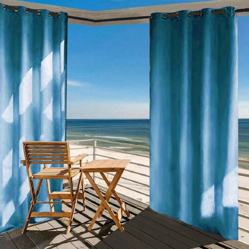 Rideaux bleus pour patio offrant une ambiance élégante et contemporaine, idéale pour profiter d'une vue sur la mer tout en préservant l'intimité. Ensemble avec chaise et table en bois sur balcon, parfait pour des moments de détente en extérieur.