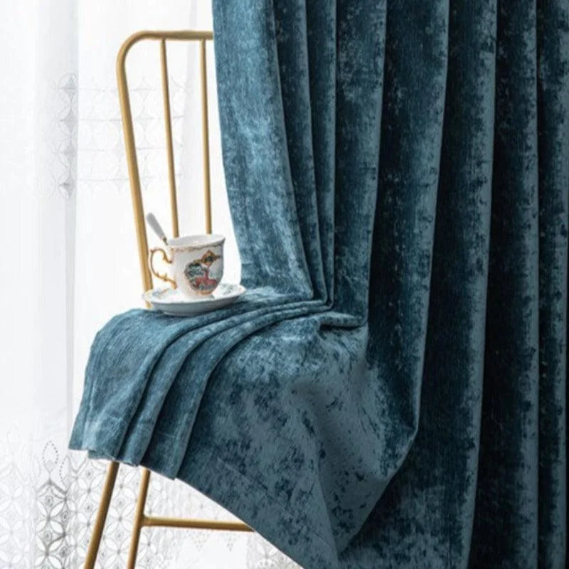 Rideau bleu élégant drapé sur une chaise dorée, avec une tasse de thé raffinée posée dessus. Idéal pour ajouter une touche de luxe et de sophistication à votre intérieur tout en apportant une ambiance chaleureuse et accueillante à votre salon ou chambre.