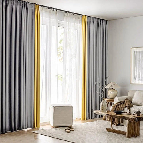 Rideaux élégants dans un salon moderne, combinant des teintes grises et jaunes pour un effet décoratif sophistiqué. Ils offrent une ambiance lumineuse et accueillante, idéale pour les intérieurs contemporains. La pièce est aménagée avec des meubles en bois et des éléments décoratifs naturels, créant un espace chaleureux et stylé.
