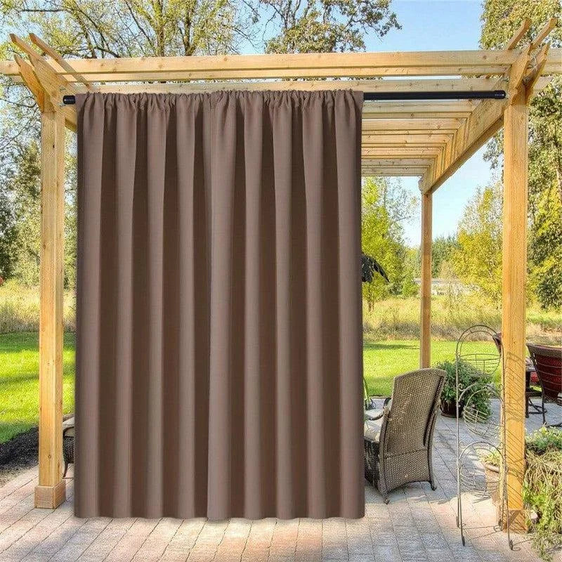 Rideau d'extérieur marron suspendu sous une pergola en bois sur une terrasse. Élément décoratif et fonctionnel pour créer de l'intimité et de l'ombre dans votre espace extérieur. Idéal pour les jardins, patios et vérandas. Accessoire parfait pour personnaliser et optimiser votre aménagement extérieur.