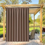 Rideau d'extérieur marron suspendu sous une pergola en bois sur une terrasse. Élément décoratif et fonctionnel pour créer de l'intimité et de l'ombre dans votre espace extérieur. Idéal pour les jardins, patios et vérandas. Accessoire parfait pour personnaliser et optimiser votre aménagement extérieur.