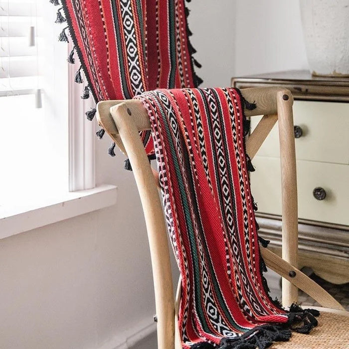 Tissu d'ameublement décoratif aux motifs traditionnels géométriques rouges et noirs, idéal pour ajouter une touche de couleur et d'originalité à votre intérieur, présenté sur une chaise en bois dans une pièce lumineuse.