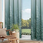 Rideaux élégants et modernes, couleur verte avec motif de branches blanches, installés dans un salon lumineux avec vue sur un jardin verdoyant. Ces rideaux apportent une touche naturelle et apaisante à la décoration intérieure, tout en créant un espace confortable et esthétique. Idéal pour ceux cherchant à ajouter une ambiance relaxante à leur intérieur.
