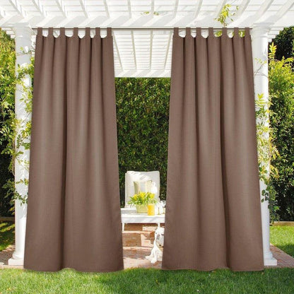 Rideaux d'extérieur marron suspendus à une pergola blanche dans un jardin. Espace détente ombragé avec des plantes vertes environnantes, idéal pour créer un coin de tranquillité et de fraîcheur en plein air.