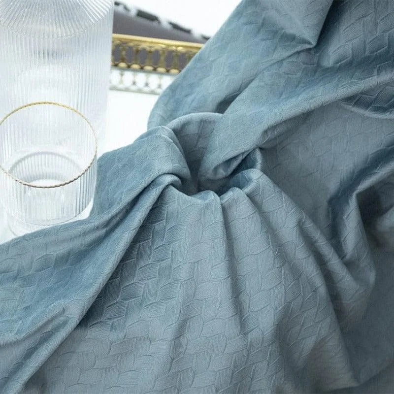 Rideau bleu texturé en gros plan, mettant en valeur un motif géométrique élégant. Idéal pour ajouter une touche de modernité et d'élégance à votre intérieur. Parfait pour les salons ou les chambres à coucher, ce rideau offre un style raffiné et contemporain. Accessoire déco incontournable pour ceux qui recherchent une ambiance chaleureuse et sophistiquée.