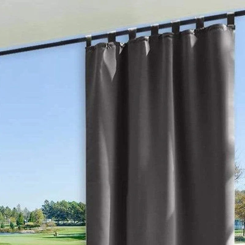 Rideau gris élégant suspendu devant une grande fenêtre avec vue sur jardin. Accessoire parfait pour améliorer la décoration intérieure et contrôler la luminosité de la pièce. Conception moderne adaptée à tous les types de fenêtres.