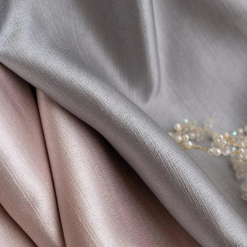 Tissu élégant dans des tons argentés et roses, idéal pour la décoration intérieure ou la confection de vêtements chic. Les nuances subtiles apportent une touche sophistiquée. Accessoire en perles visible pour un ajout luxueux. Parfait pour les amateurs de design raffiné.
