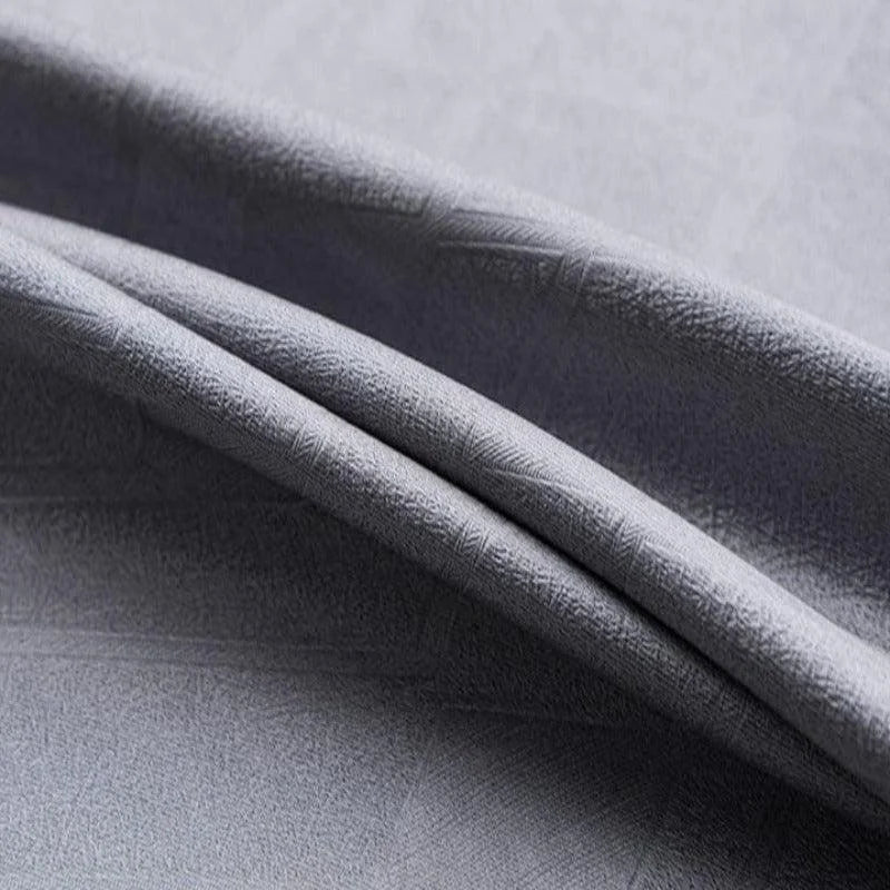 Gros plan d'un tissu gris aux plis élégants, idéal pour la confection de vêtements modernes et minimalistes, ajoutant une touche de sophistication à votre garde-robe. Découvrez la qualité de ce textile qui assure confort et style intemporel. Parfait pour des créations vestimentaires tendance.