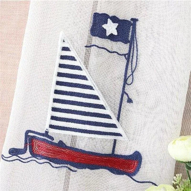 Image d'un design nautique avec un voilier à voiles rayées bleu marine et blanches, arborant un drapeau avec une étoile, idéal pour une décoration maritime élégante. Convient parfaitement pour une chambre d'enfant à thème marin ou comme accessoire décoratif dans une maison de bord de mer.