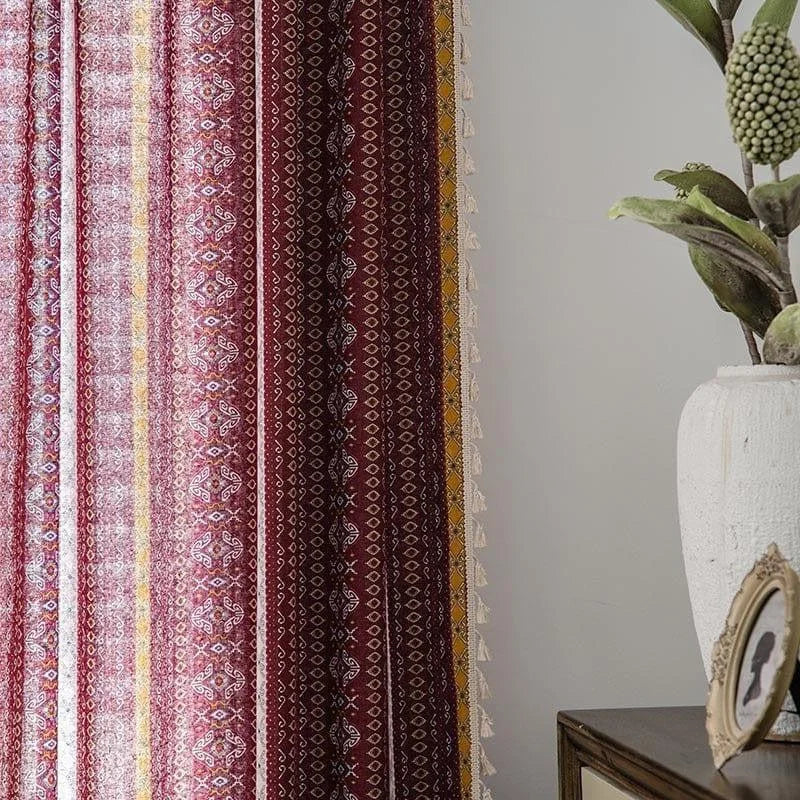 Rideaux décoratifs à motifs ethniques rouges et jaunes pour un intérieur chaleureux et élégant, accompagnés d'une plante verte en pot et d'un cadre sur une commode.