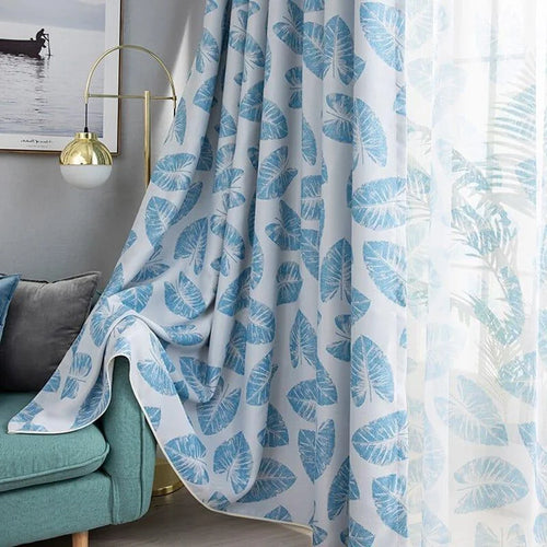 Rideaux élégants à motifs de feuilles bleues pour une décoration intérieure moderne. Idéaux pour ajouter une touche de fraîcheur et de style dans le salon ou la chambre. S'harmonisent parfaitement avec un canapé bleu et un éclairage contemporain.