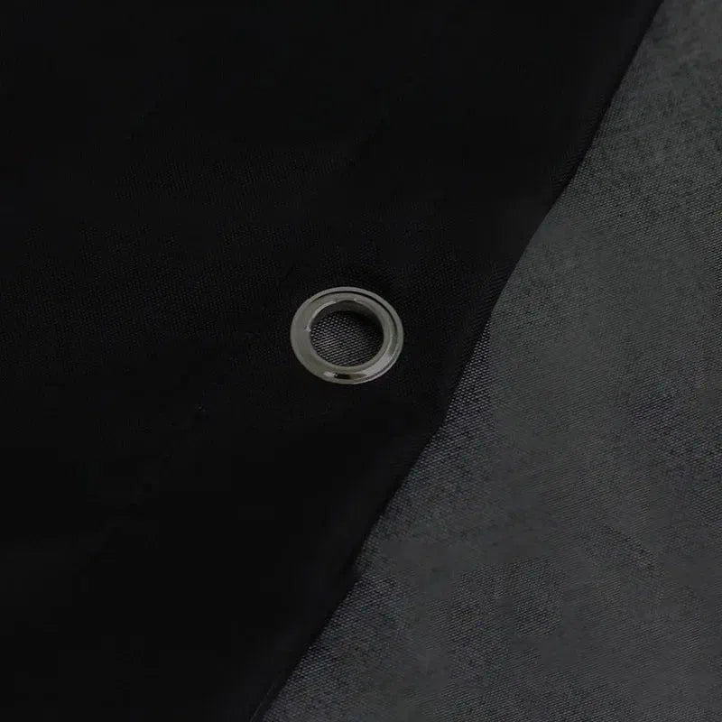 Oeillet métallique sur tissu noir, détail de bâche robuste pour usage extérieur, protection solaire et résistance aux intempéries, idéal pour le jardinage et le camping, accessoire résistant pour accroche et fixation sécurisée.