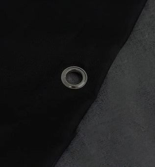 Oeillet métallique sur tissu noir, détail de bâche robuste pour usage extérieur, protection solaire et résistance aux intempéries, idéal pour le jardinage et le camping, accessoire résistant pour accroche et fixation sécurisée.