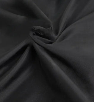 Drapé élégant de tissu noir offrant un pli fluide et raffiné, idéal pour la confection de vêtements chics et intemporels, parfait pour une garde-robe sophistiquée.
