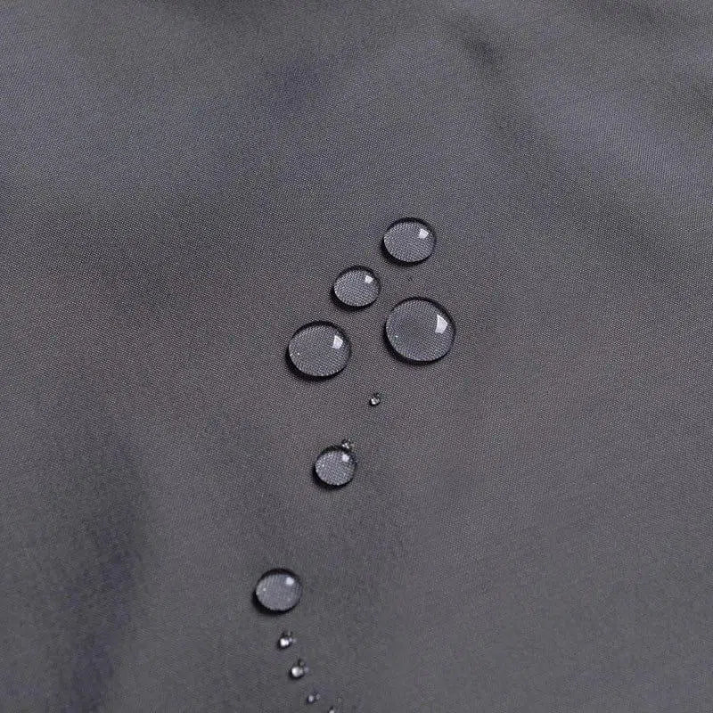 Gouttes d'eau sur une surface grise, démontrant une résistance à l'eau, idéale pour les vêtements ou accessoires d'extérieur, offrant protection et durabilité face à l'humidité.