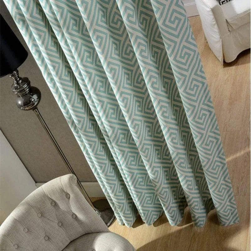 Rideaux à motif géométrique turquoise et blanc pendus dans un salon moderne, accompagnés d'un fauteuil beige et d'une lampe sur pied en métal pour une décoration intérieure contemporaine et élégante.