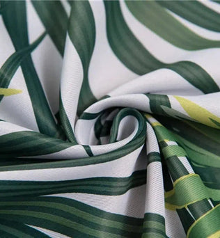 Image montrant un tissu avec un motif de feuilles tropicales vertes sur fond clair, idéal pour une décoration intérieure exotique, ajoutant une touche naturelle et chic à tout espace de vie.