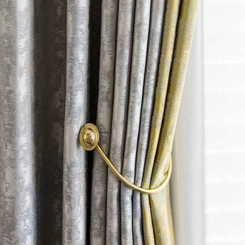 Rideaux élégants avec motif en deux tons, maintenus par un embrasse doré, conçus pour apporter une touche de sophistication à votre intérieur tout en contrôlant la lumière naturelle dans la pièce. Idéal pour le salon ou la chambre, cet accessoire ajoute une note de raffinement à votre décoration.