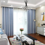 Rideaux bleu clair modernes pour salon, installation élégante devant une grande baie vitrée, offrant une ambiance lumineuse et sophistiquée. Décoration intérieure contemporaine avec canapé gris, table basse noire et tapis multicolore, idéale pour transformer votre espace de vie avec style. Lustre design et accessoires décoratifs ajoutent une touche de raffinement à votre maison.
